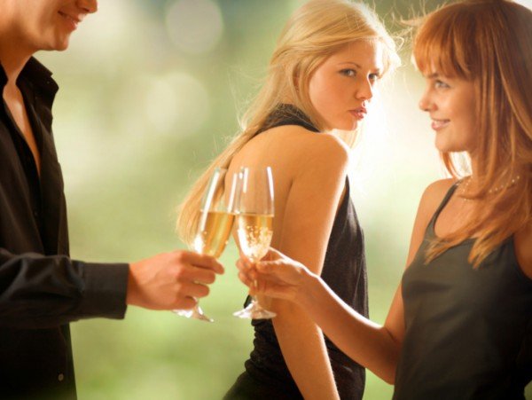 Young couple holding glasses with champagne and woman looking at