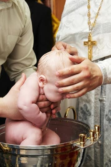 baby baptism with water in font